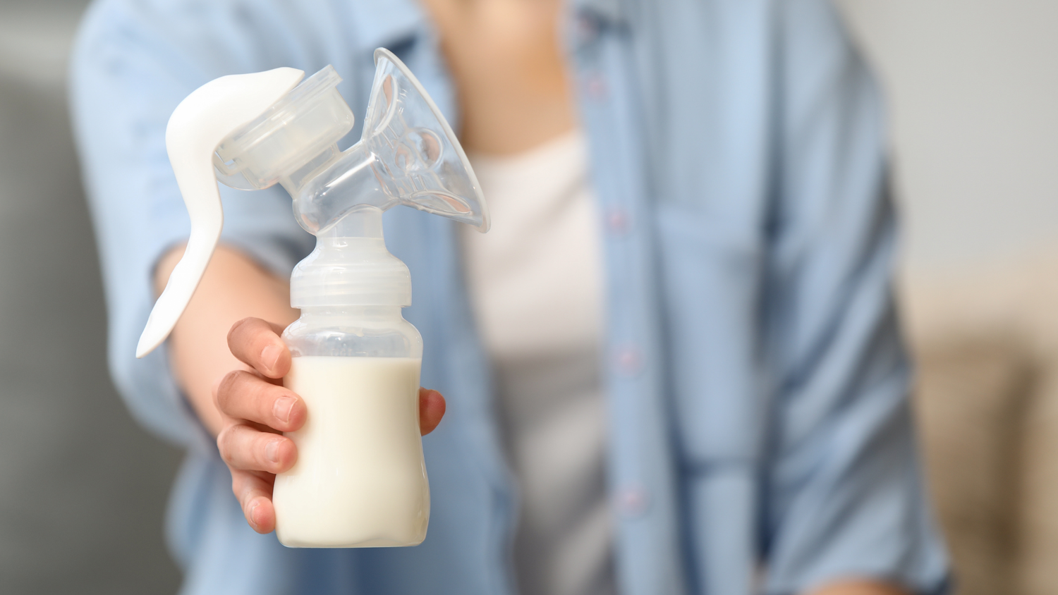 Mom holding manual breast pump with expressed breast milk bottle