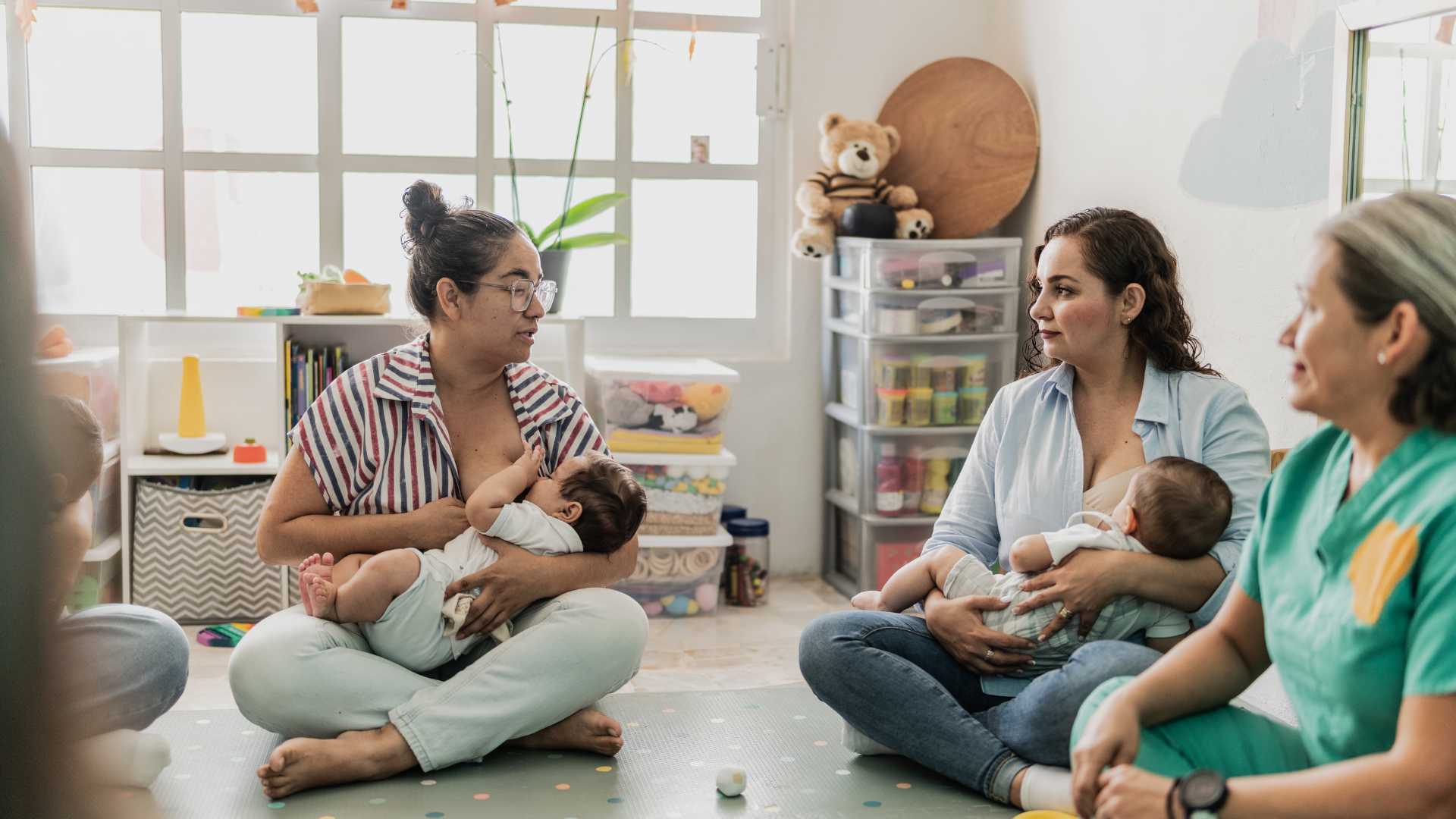 Mothers nursing babies while discussing breastfeeding diet myths in a group