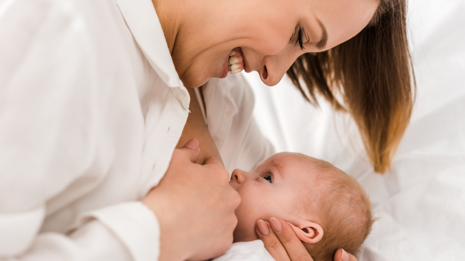 New mother gazing at baby while breastfeeding in soft light