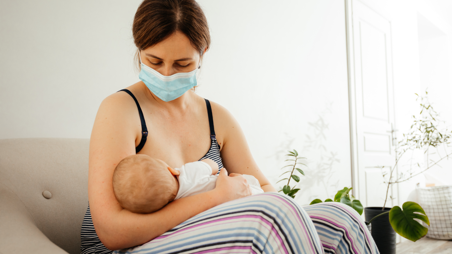 Sick mother in face mask breastfeeding her infant at home