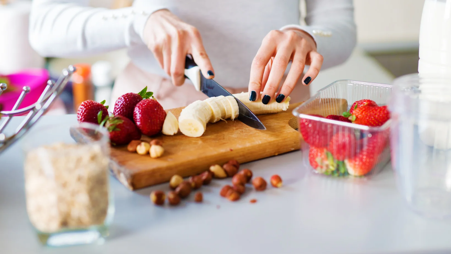 Slicing banana and preparing strawberries on a cutting board 