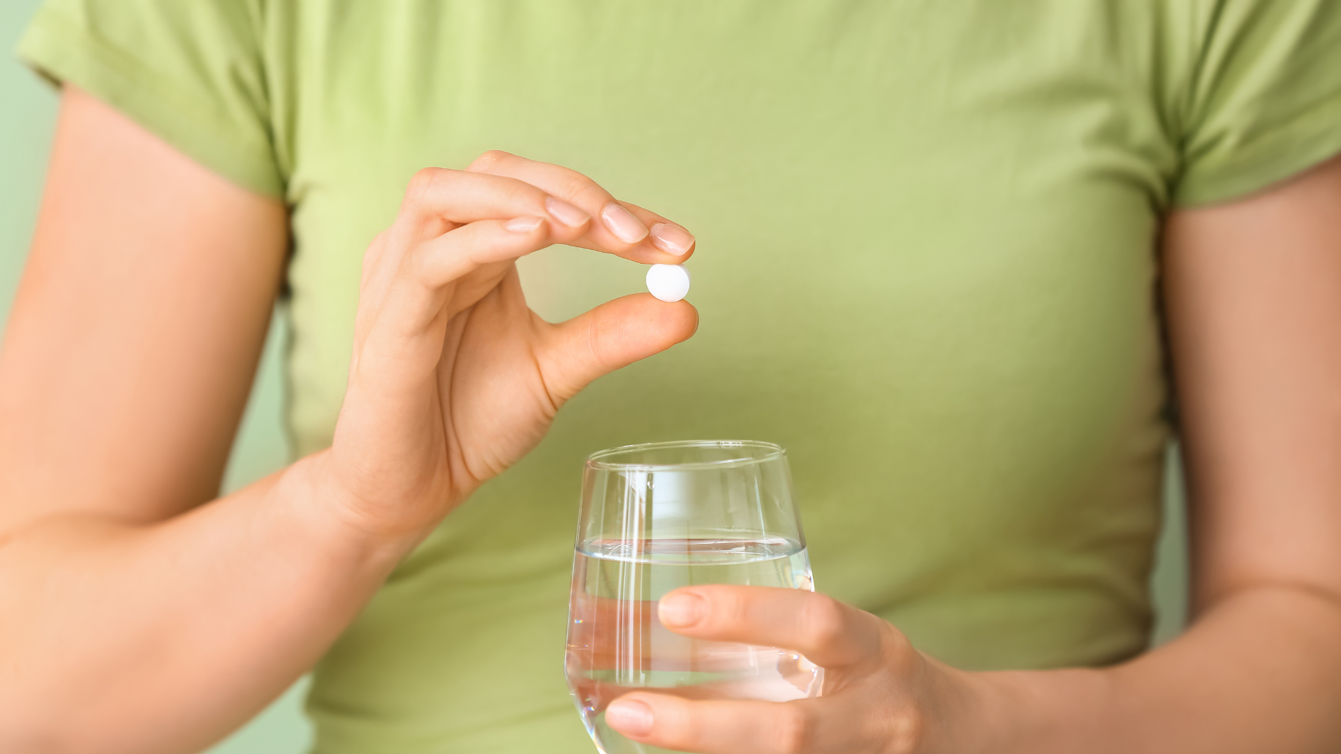 Woman holding ibuprofen pill and water glass while breastfeeding, considering medication safety
