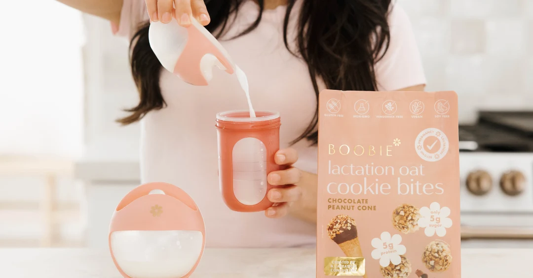 Woman pouring milk next to a bag of BOOBIE lactation oat cookie bites