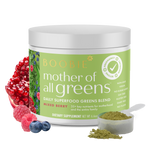 A container of 'Mother of All Greens' dietary supplement with a scoop of the powder and pieces of berry, pomegranate and blueberries displayed in the foreground.